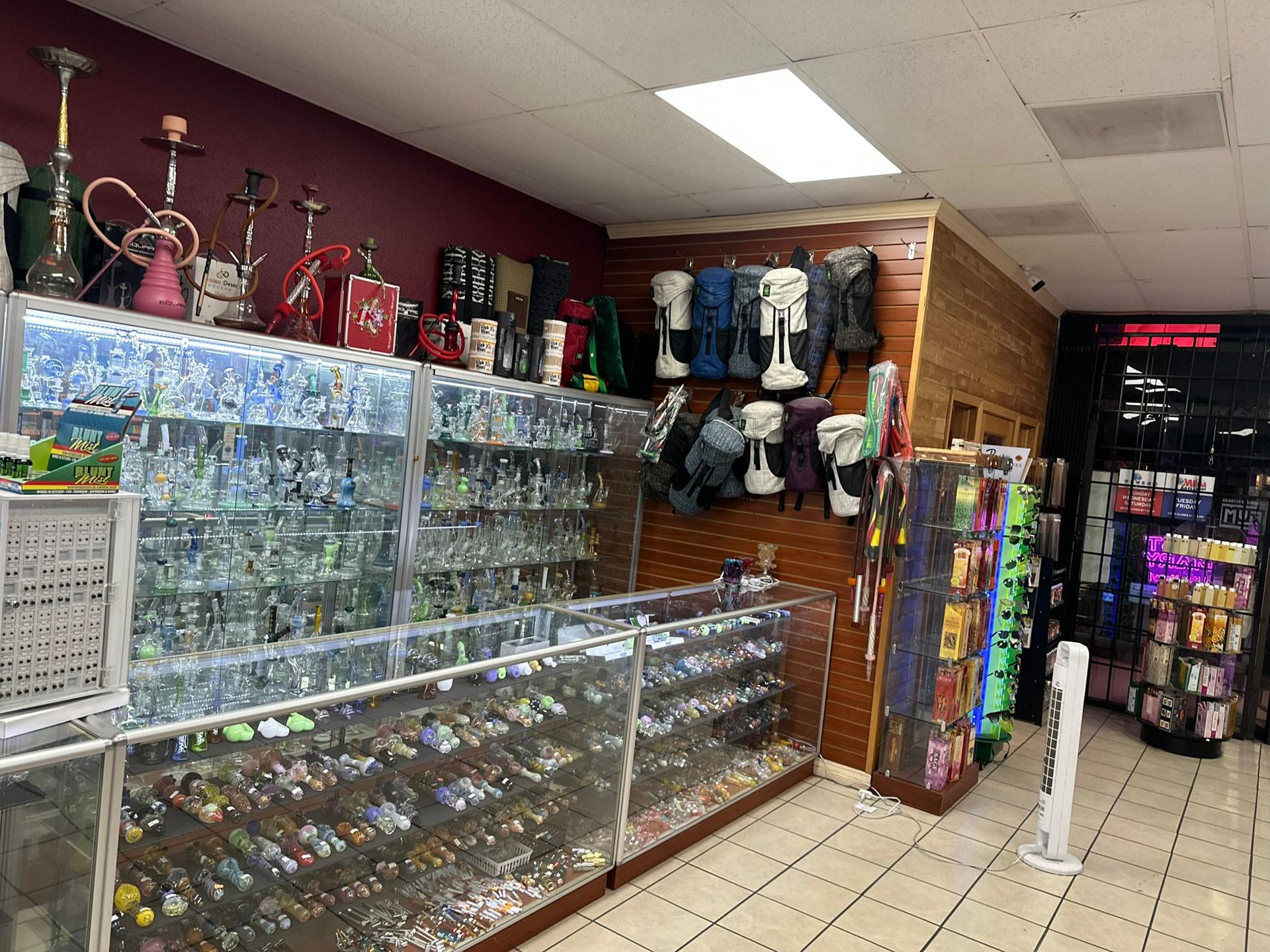 Inside Sam's Smoke & Vape: glass display cases of pipes and rigs with hookahs on top