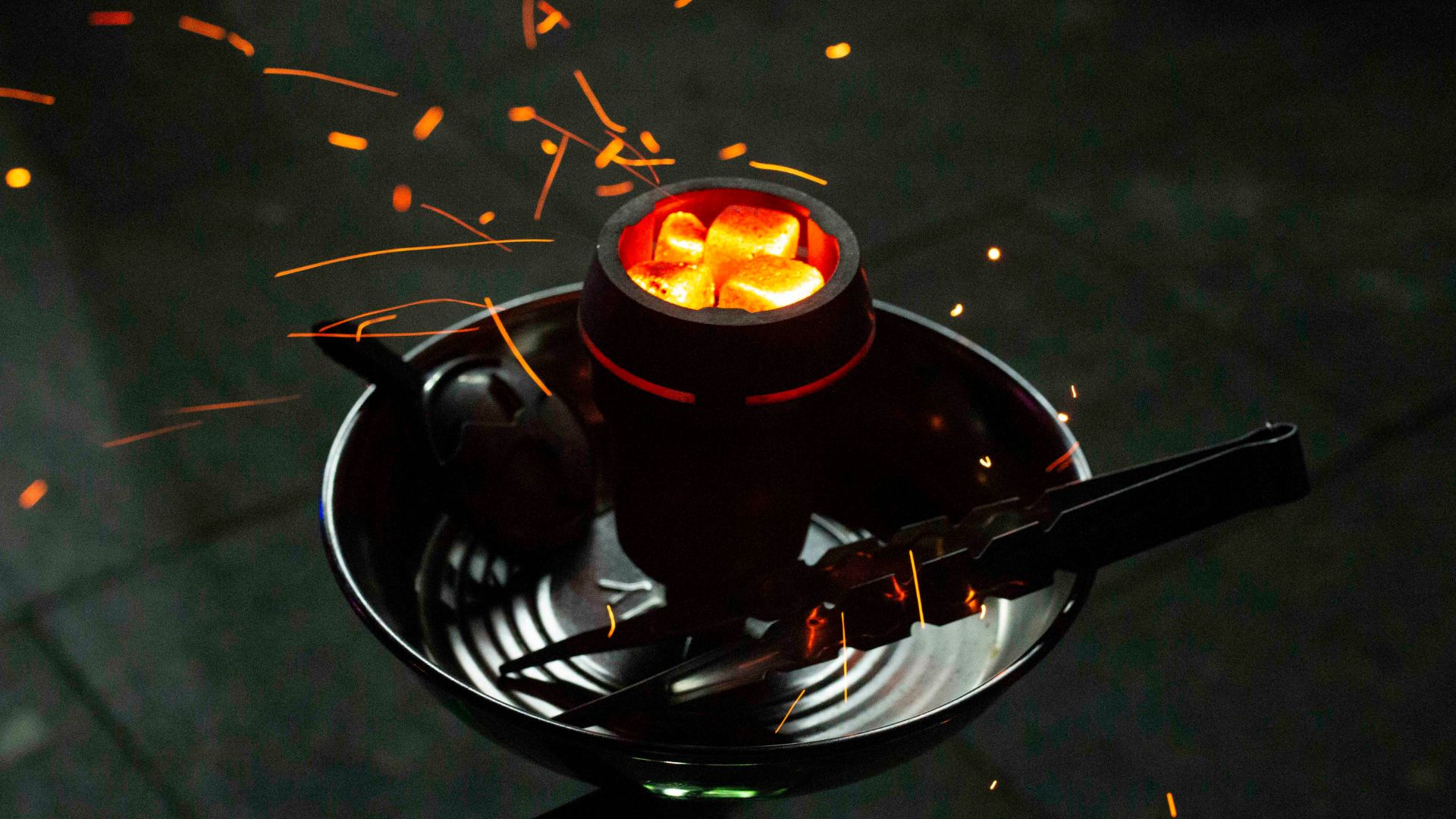 Glowing hot coals in a hookah bowl with sparks flying